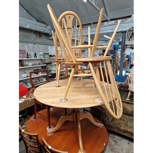 1114 - A modern Ercol light elm dining table and four swan back chairs, height 72cm and diameter 120cm.