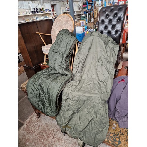 172 - Two camoflage camping bags, containing a sleeping bag & sleeping bag rain cover in each bag.