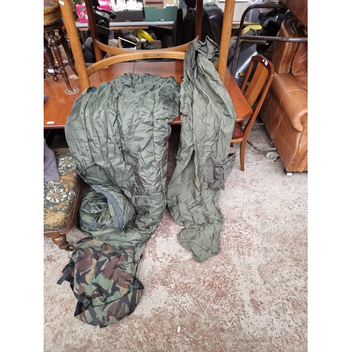 172 - Two camoflage camping bags, containing a sleeping bag & sleeping bag rain cover in each bag.