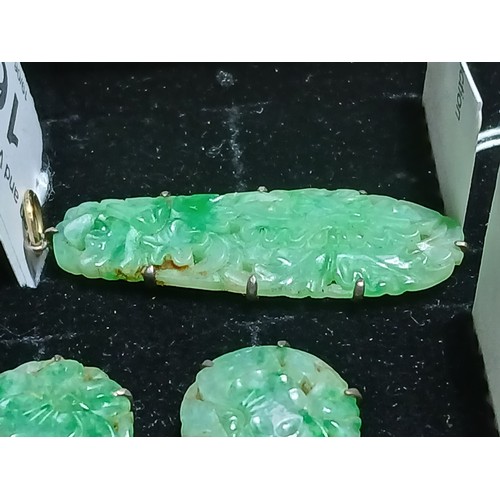 16 - A carved jadeite jade pendant and matching earrings, pendant length 42mm, earring diameter 17mm.