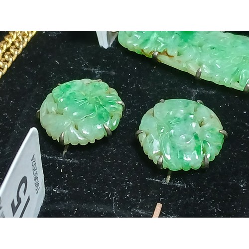 16 - A carved jadeite jade pendant and matching earrings, pendant length 42mm, earring diameter 17mm.