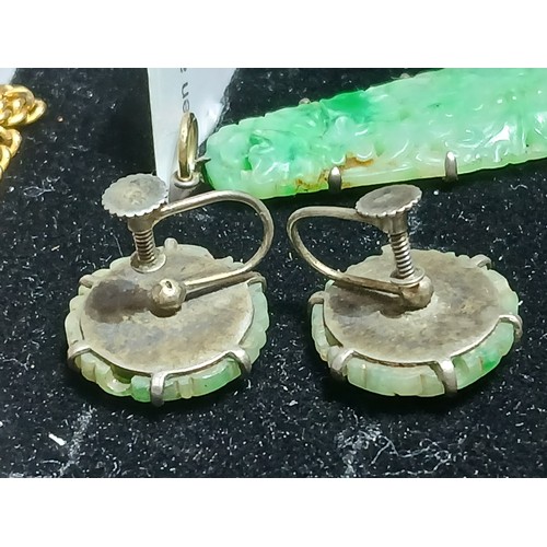 16 - A carved jadeite jade pendant and matching earrings, pendant length 42mm, earring diameter 17mm.