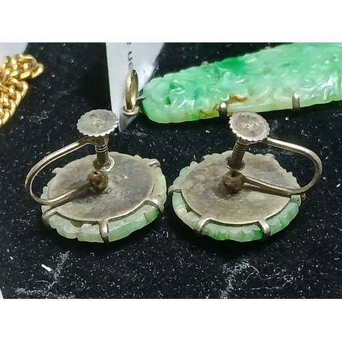 16 - A carved jadeite jade pendant and matching earrings, pendant length 42mm, earring diameter 17mm.