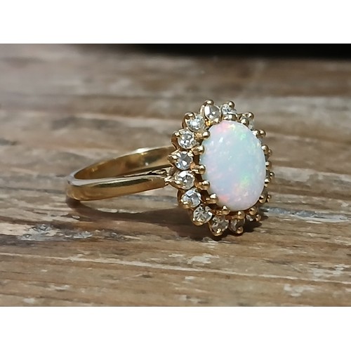 62 - An 18ct gold opal and diamond ring, the central opal cabochon measuring approximately 9.2mm x 7mm, d... 