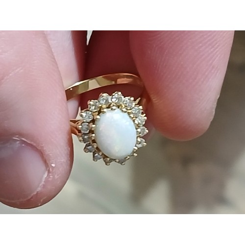 62 - An 18ct gold opal and diamond ring, the central opal cabochon measuring approximately 9.2mm x 7mm, d... 