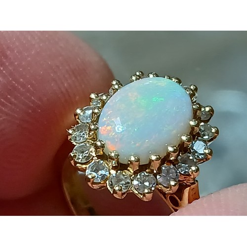 62 - An 18ct gold opal and diamond ring, the central opal cabochon measuring approximately 9.2mm x 7mm, d... 