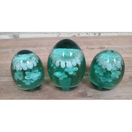 430 - A group of three Victorian green glass dumps or paperweights, heights 11cm to 14cm.