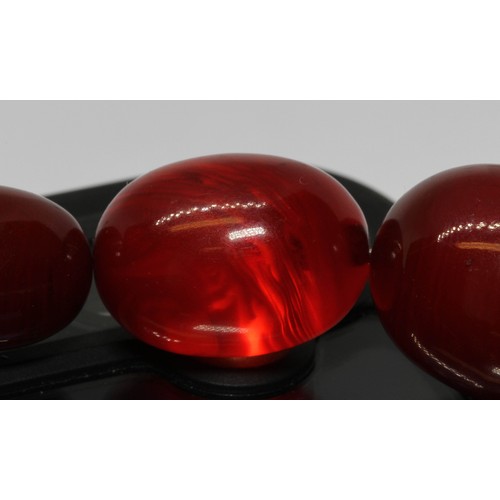 71 - A single strand of graduated marbled cherry bakelite beads, the oval shaped beads ranging in length ... 