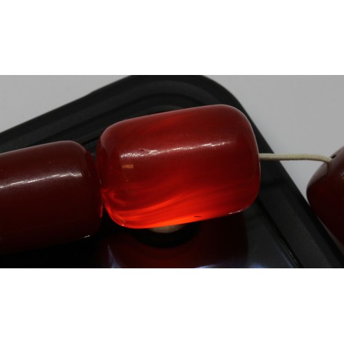 70 - A single strand of graduated barrel shaped and marbled cherry bakelite beads, the beads ranging in l... 