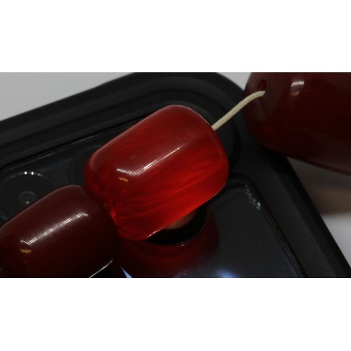 70 - A single strand of graduated barrel shaped and marbled cherry bakelite beads, the beads ranging in l... 