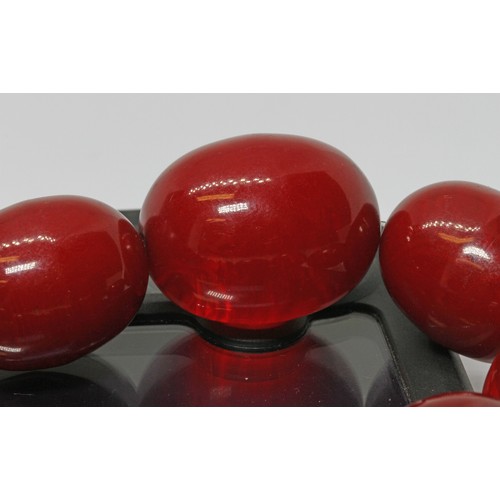 71 - A single strand of graduated marbled cherry bakelite beads, the oval shaped beads ranging in length ... 