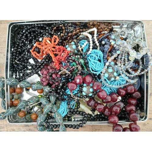 142 - A tin of assorted costume jewellery necklaces including cherry coloured, eastern, turquoise etc.