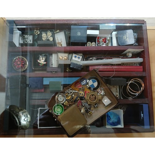 165 - A display case of costume jewellery and badges etc.