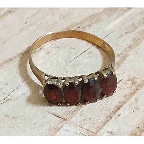 268 - A yellow metal ring set with four garnets, indistinctly marked, gross weight 1.7g.