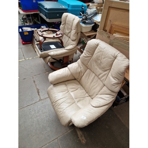 1023 - A pair of Ekornes cream leather 'Stressless' reclining armchairs and matching footstool.