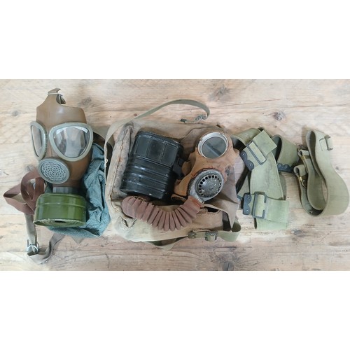 61 - A box of militaria comprising two gas masks and two belts.