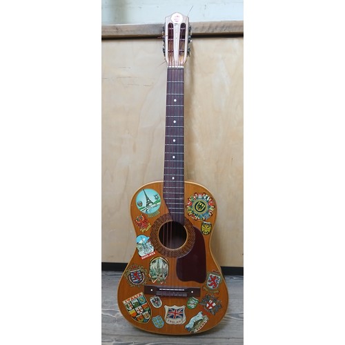 151 - An acoustic guitar with Aquila Rubino strings decorated with European city badges.