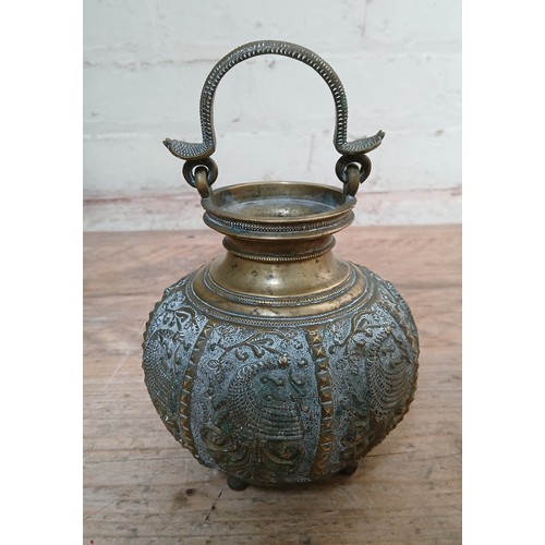 176 - An Indian brass vessel, circa 1900, bulbous form decorated in relief with peacocks, swing handle mod... 