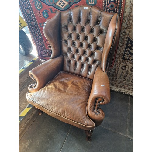 995 - A tan leather Chesterfield Queen Anne style wingback armchair.