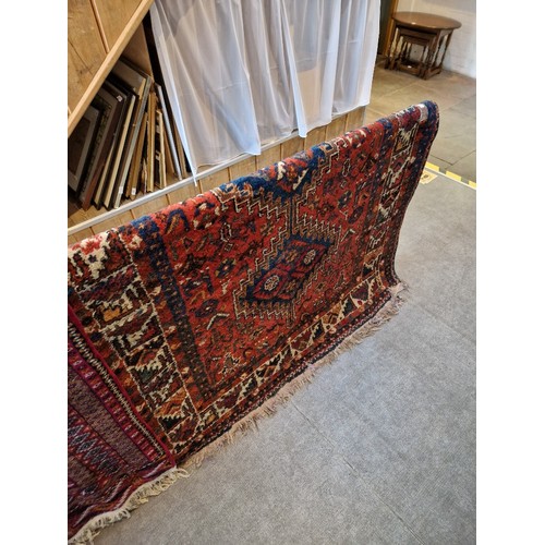 1001 - A vintage Eastern wool carpet, red ground with geometric design, 212cm x 147cm (approx).