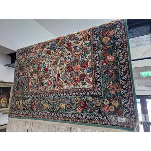 1008 - An Iranian wool carpet, green ground decorated with flowers & birds, 180cm x 108cm (approx).