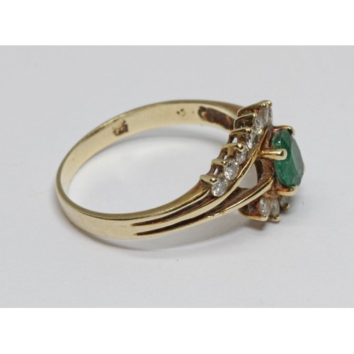 41 - An emerald and diamond cross over ring, the central oval faceted stone weighing approximately 0.44ct... 