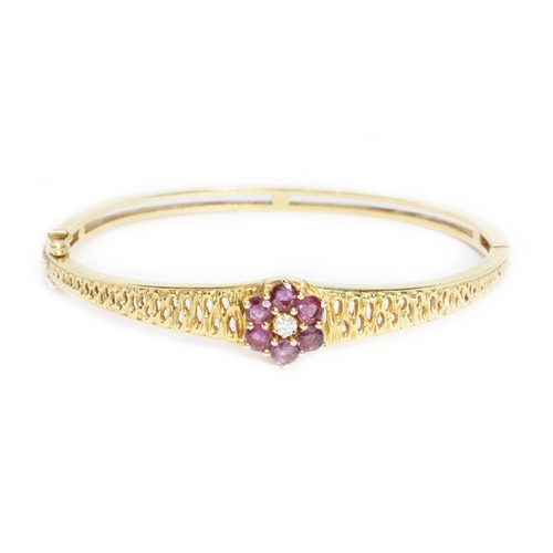 509 - A diamond and ruby bangle, the cluster measuring approximately 12mm in diameter, yellow metal marked... 