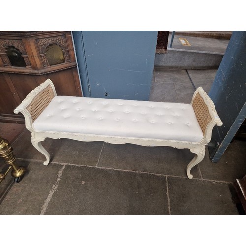 849 - A Laura Ashley style cream painted and bergere window seat or bench, length 134cm.