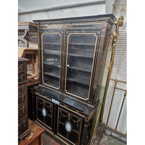 852 - A fine late Victorian Aesthetic ebonised and parcel gilt inlaid cabinet bookcase set with Wedgwood t... 