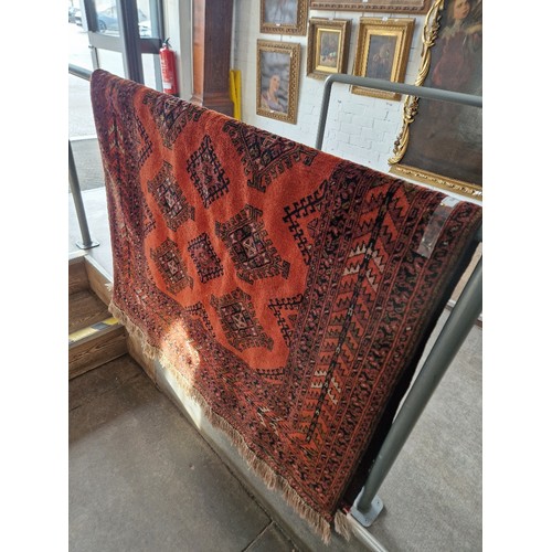 843 - An Afghan wool carpet, red ground, geometric design, 204cm x 132cm (approx).