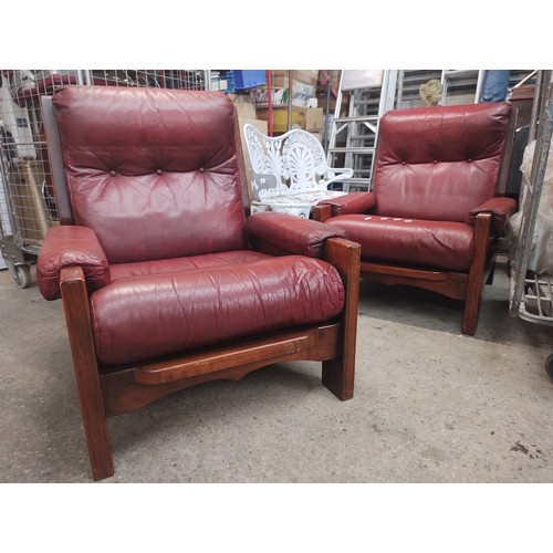 999 - A pair of oak and red leather armchairs.