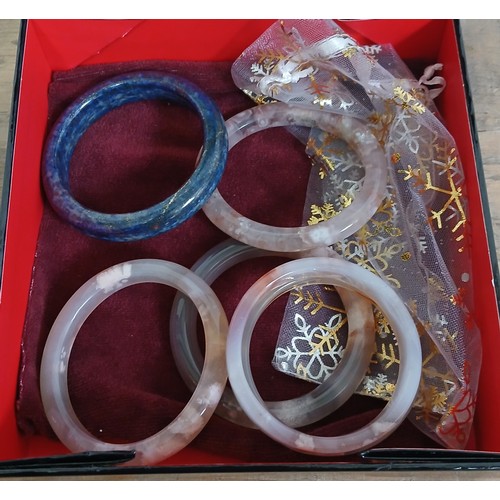 649 - A group of six hard stone bangles including lapis lazuli.