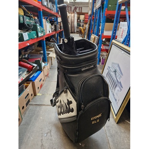 211A - A Titleist golf bag with Ernie Els embroidered on the side with a Taylor made golf umbrella.
