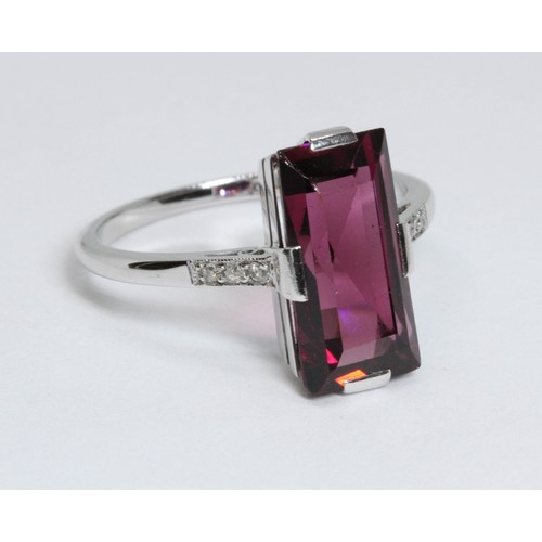 5 - An Art Deco style garnet and diamond ring, the central rectangular mixed cut purple stone measuring ... 