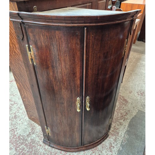 980 - A Georgian oak bow front corner cabinet.