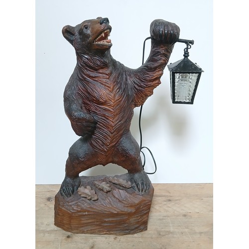 615 - A Black Forest table lamp modelled as a bear stood on hind legs and holding a lantern, base with thr... 