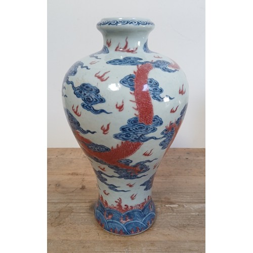 614 - A Chinese porcelain baluster vase decorated in red and blue underglaze depicting a dragon amongst cl... 