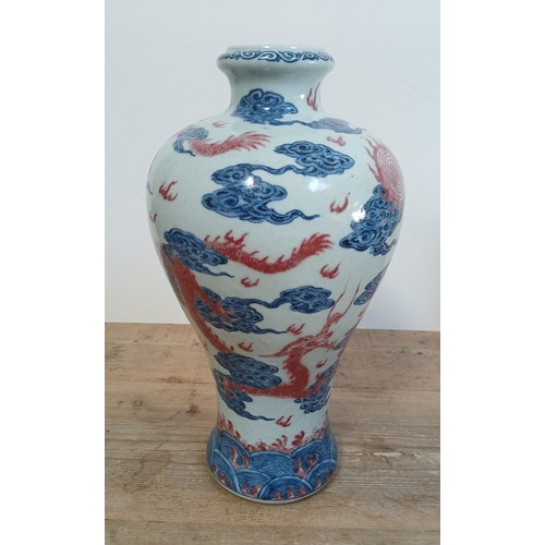 614 - A Chinese porcelain baluster vase decorated in red and blue underglaze depicting a dragon amongst cl... 