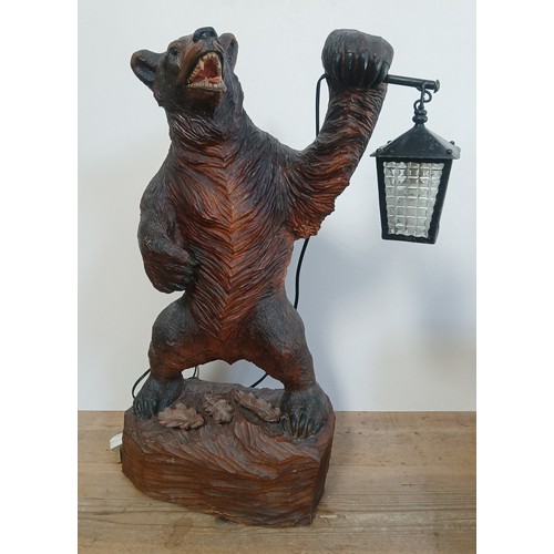 615 - A Black Forest table lamp modelled as a bear stood on hind legs and holding a lantern, base with thr... 
