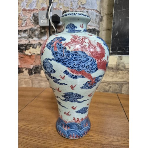 614 - A Chinese porcelain baluster vase decorated in red and blue underglaze depicting a dragon amongst cl... 