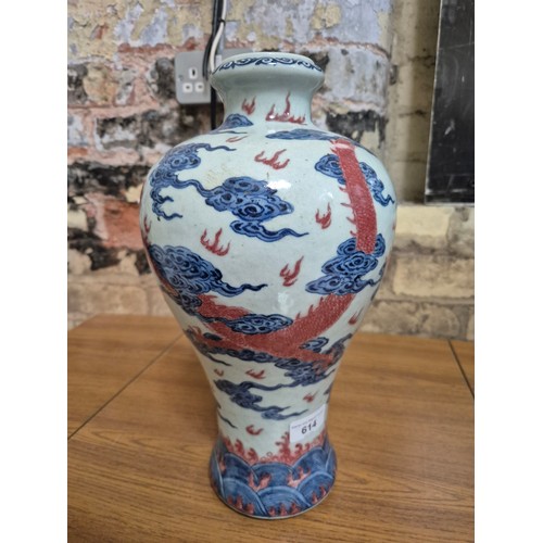 614 - A Chinese porcelain baluster vase decorated in red and blue underglaze depicting a dragon amongst cl... 