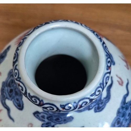 614 - A Chinese porcelain baluster vase decorated in red and blue underglaze depicting a dragon amongst cl... 