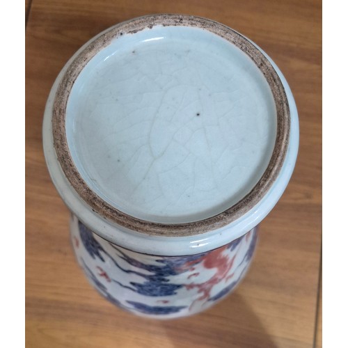 614 - A Chinese porcelain baluster vase decorated in red and blue underglaze depicting a dragon amongst cl... 