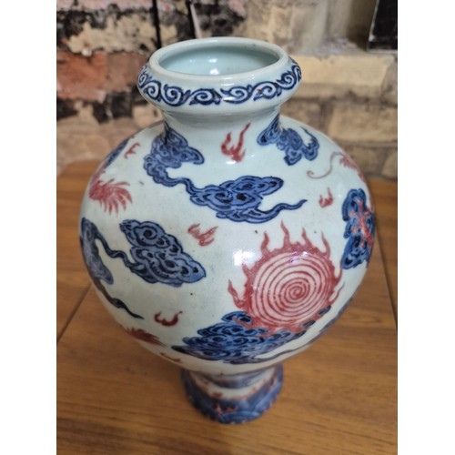 614 - A Chinese porcelain baluster vase decorated in red and blue underglaze depicting a dragon amongst cl... 