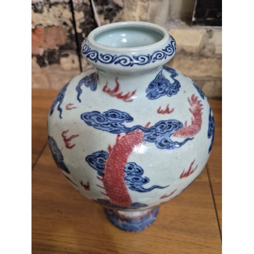 614 - A Chinese porcelain baluster vase decorated in red and blue underglaze depicting a dragon amongst cl... 