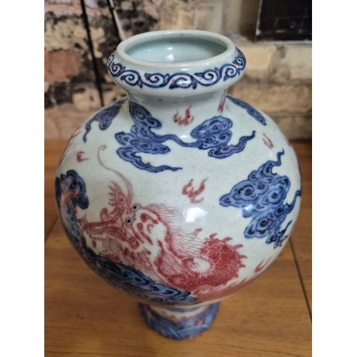 614 - A Chinese porcelain baluster vase decorated in red and blue underglaze depicting a dragon amongst cl... 