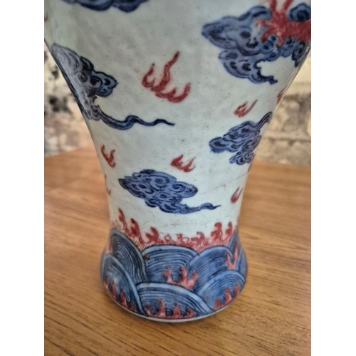 614 - A Chinese porcelain baluster vase decorated in red and blue underglaze depicting a dragon amongst cl... 