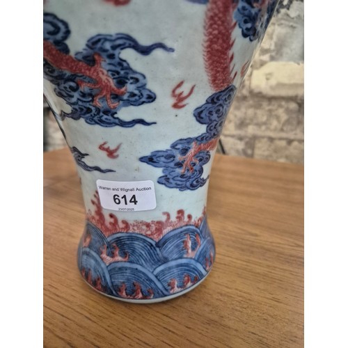 614 - A Chinese porcelain baluster vase decorated in red and blue underglaze depicting a dragon amongst cl... 