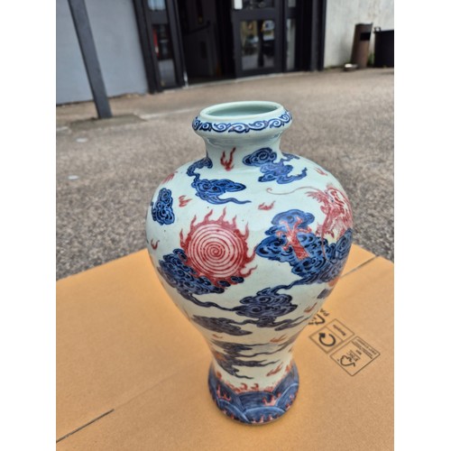 614 - A Chinese porcelain baluster vase decorated in red and blue underglaze depicting a dragon amongst cl... 