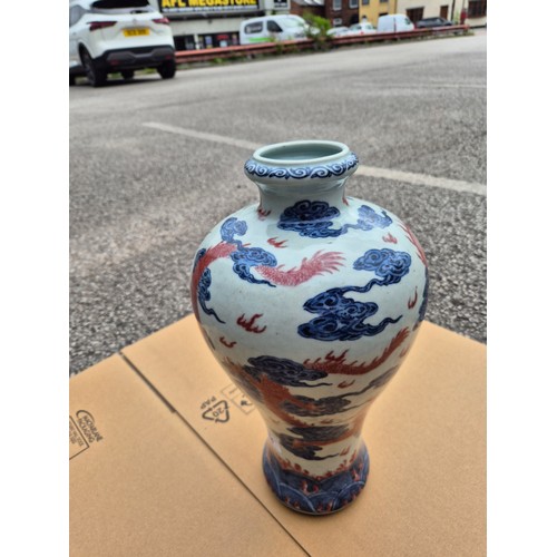 614 - A Chinese porcelain baluster vase decorated in red and blue underglaze depicting a dragon amongst cl... 